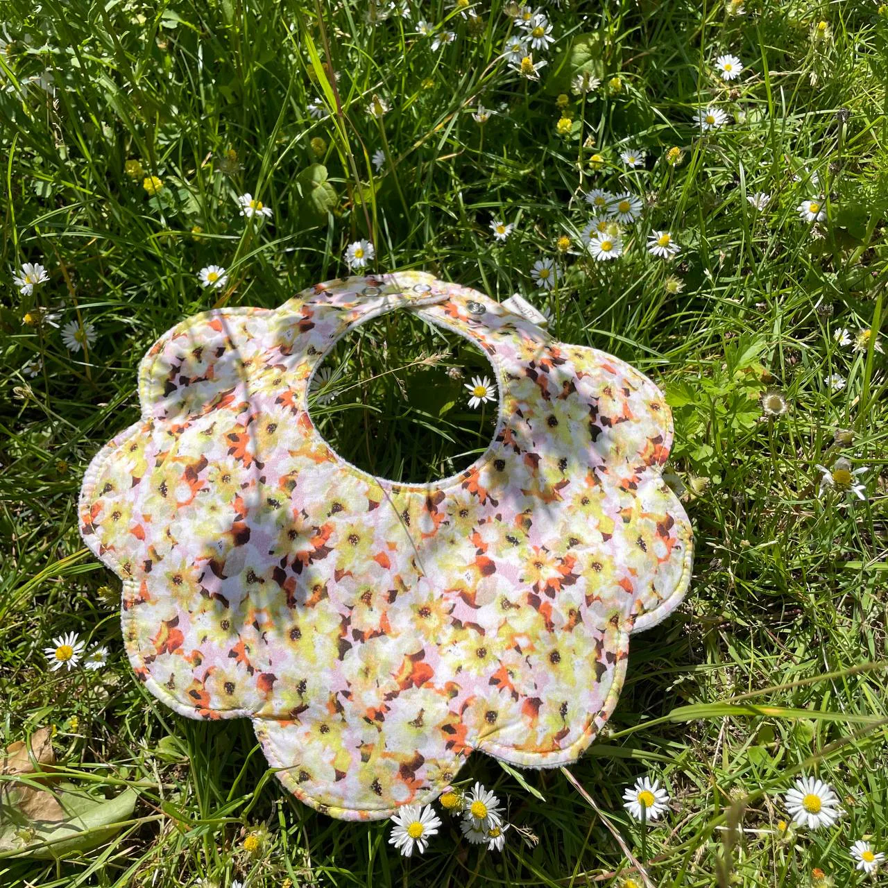 Gentle Nature — a flower-shaped bib in soft cream floral cotton