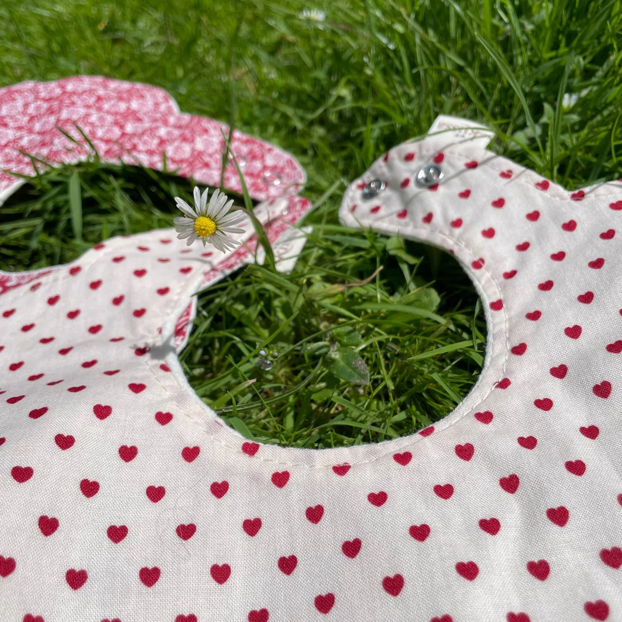 Little Hearts — a white flower-shaped bib with tiny red hearts