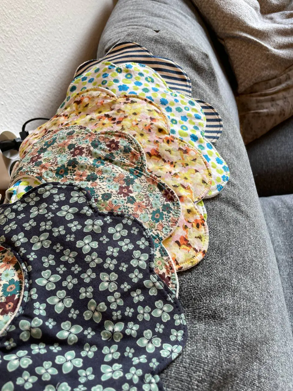 En stak blomsterhagesmække over sofaens armlæn