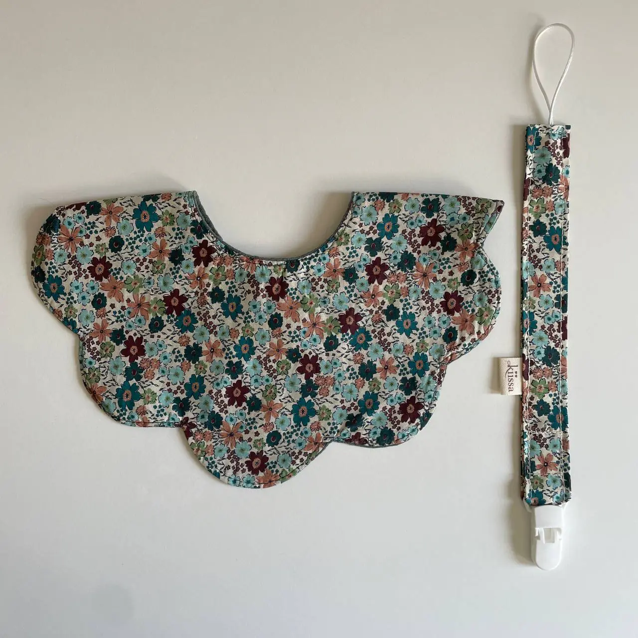 A floral bib with its matching pacifier clip