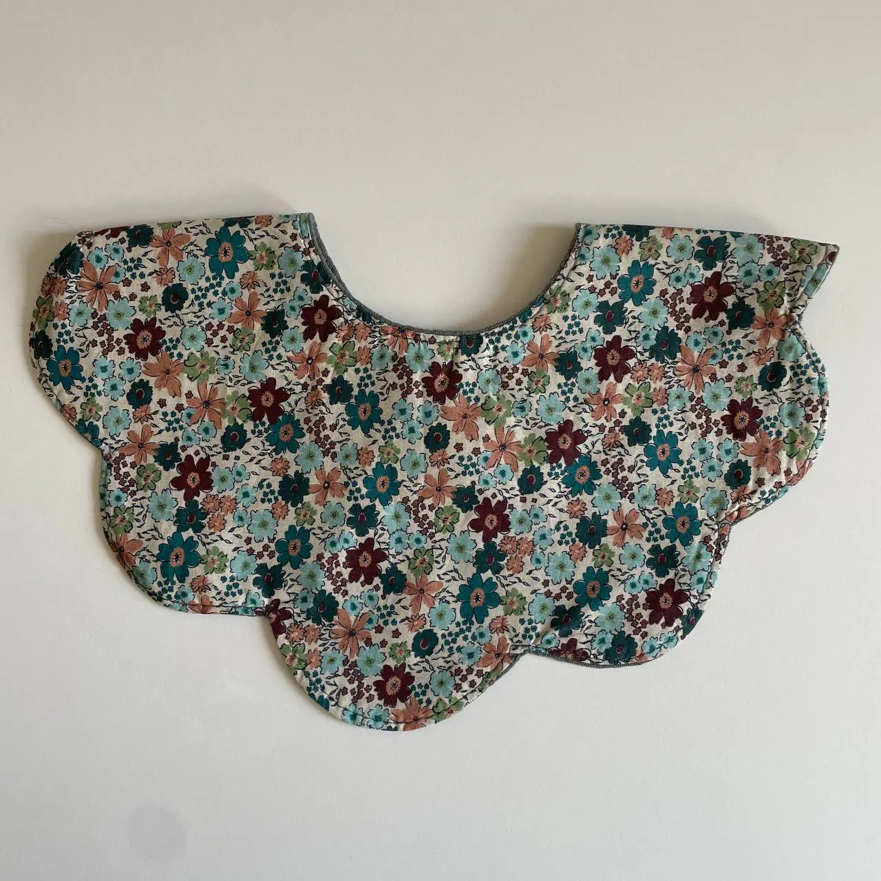 A wide scalloped collar laid flat on cream